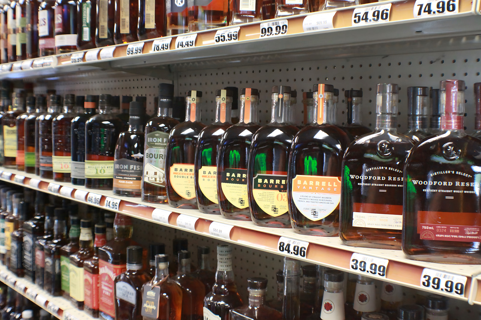 Bourbon shelves inside Bay Party Store — Barrell, Woodford Reserve, Iron Fish